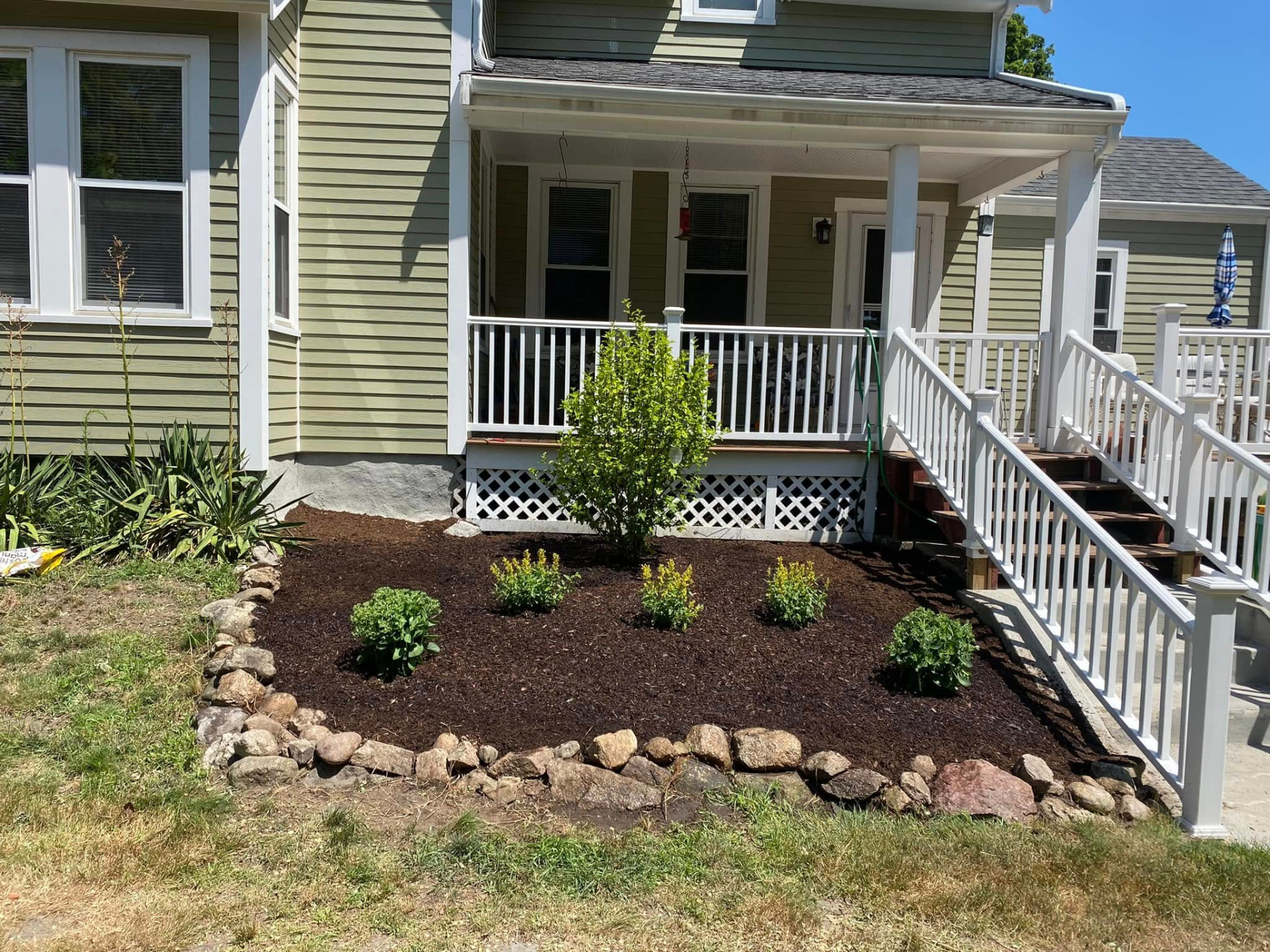 Freshly installed dark mulch in an edged bed around green shrubs