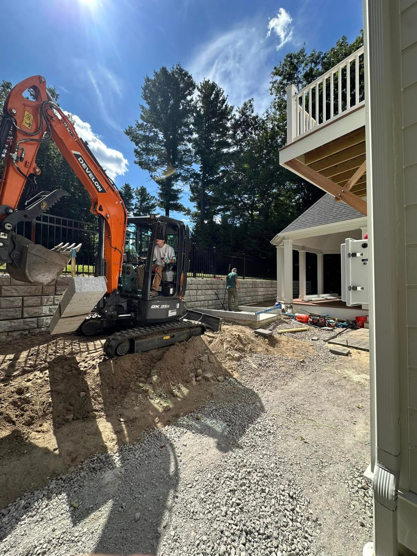 Mini excavator setting grade behind a new block retaining wall
